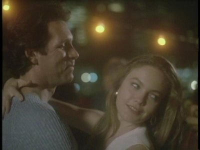 A woman rests her arm around a man against a background of lights in Lady Beware (1987).
