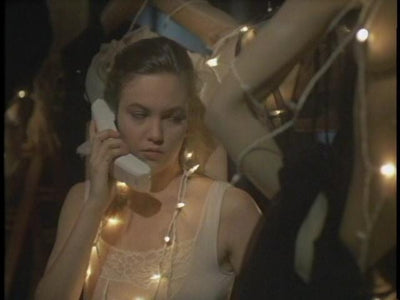 A woman holds a telephone receiver among mannequins and string lights in Lady Beware (1987).