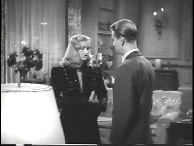A woman and a man facing one another in a sitting room in The Blue Dahlia.