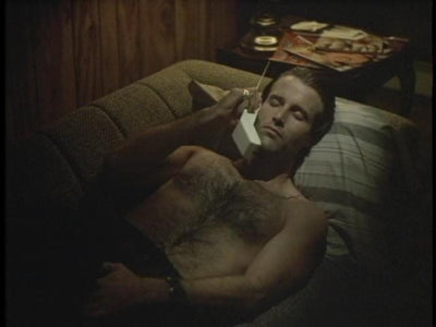A man reclines on a sofa while talking on a cordless telephone in Lady Beware (1987).